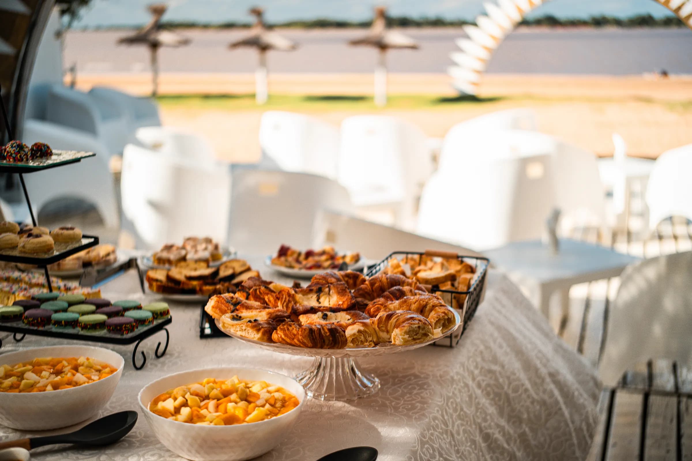 El buffet del desayuno servido frente al río, con las sombrillas de paja de fondo
