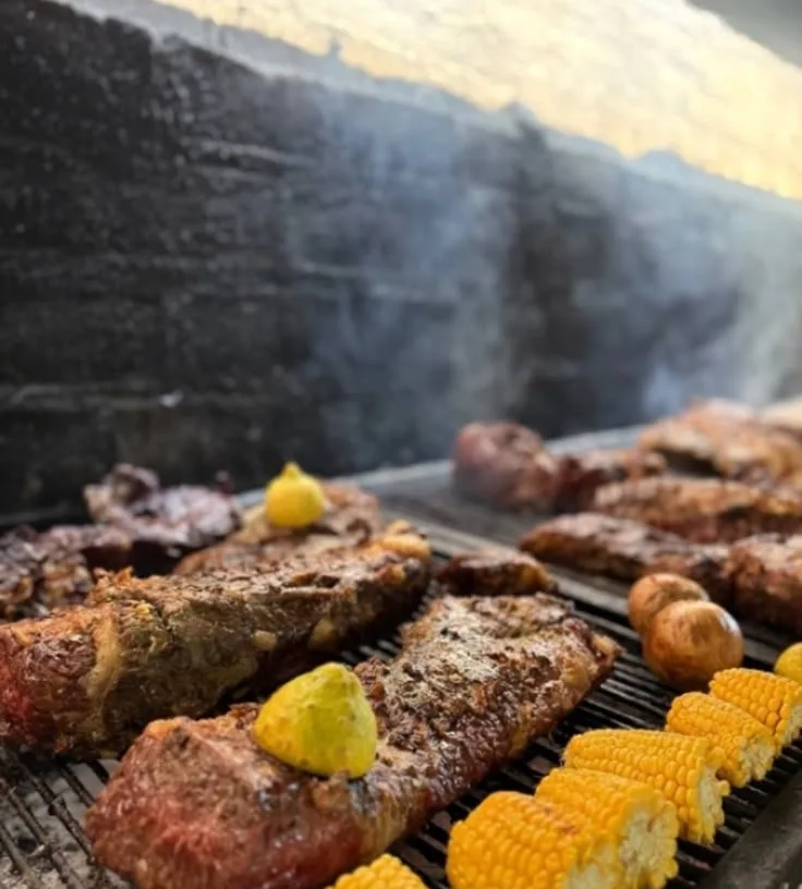 Asado y choclos sobre la parrilla del quincho, con humo